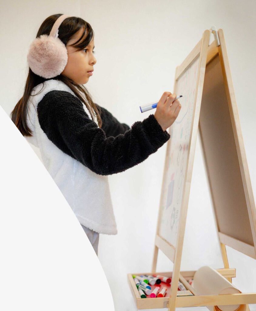 A child concentrated without distraction while drawing on a board.
